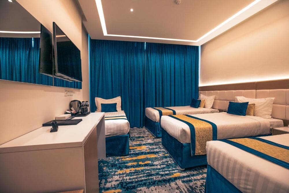 Dhomë me katër shtretër dhe perde blu në Taj Park Hotel