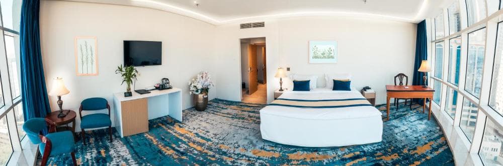 Dhomë e ndritshme me krevat, lule dhe dritare në Taj Park Hotel